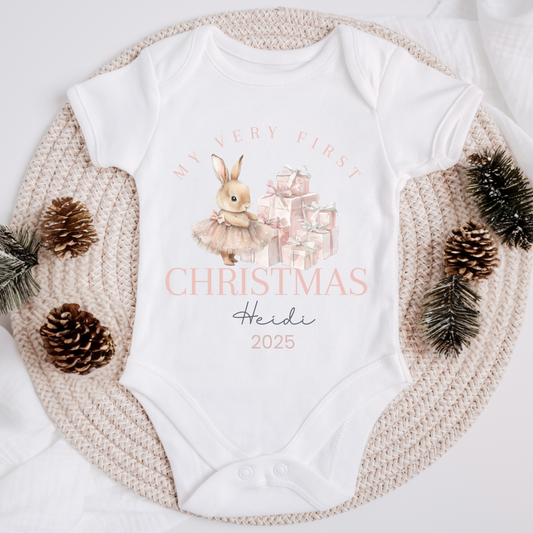 White baby onesie with Christmas design and text, surrounded by decorative elements on a white background.