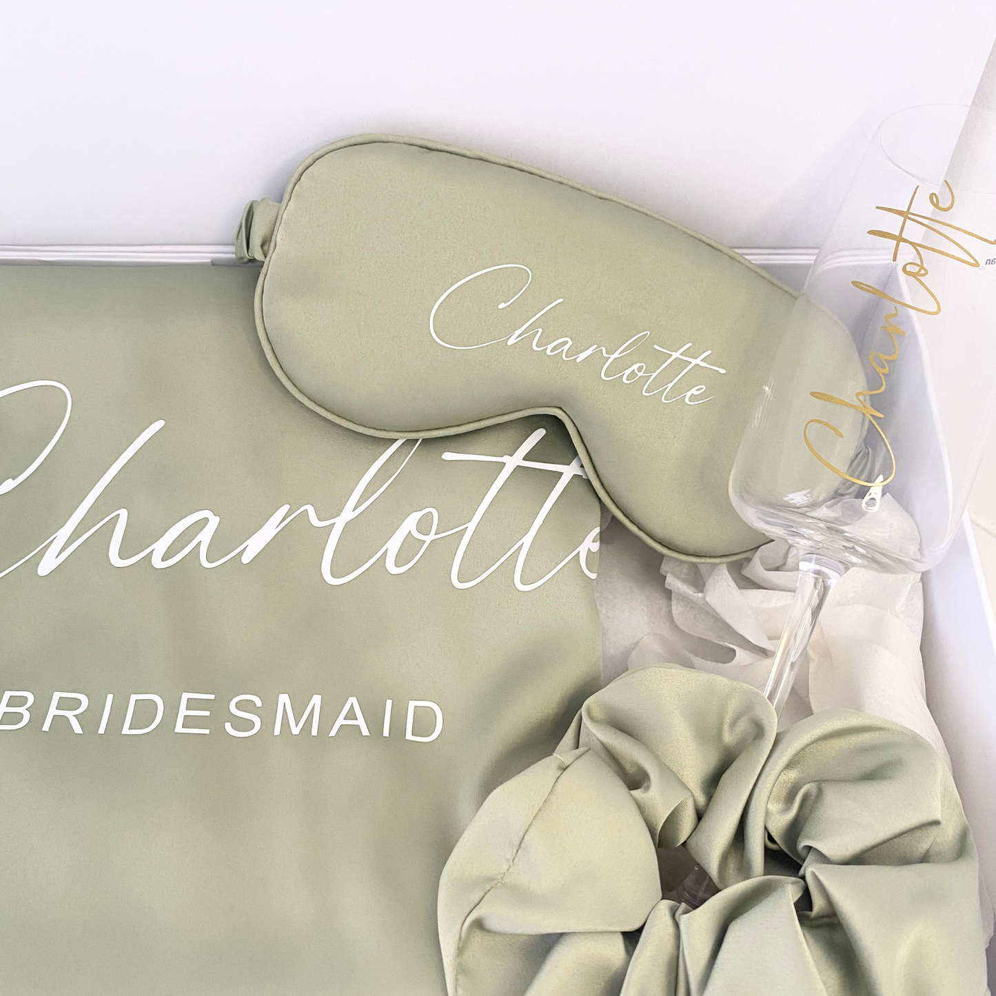 Close-up of satin bridesmaid robe set with eye mask and champagne glass